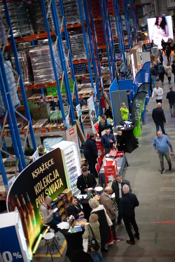Targi w Gdańsku z wystawcami, stoiskami i uczestnikami w hali targowej.