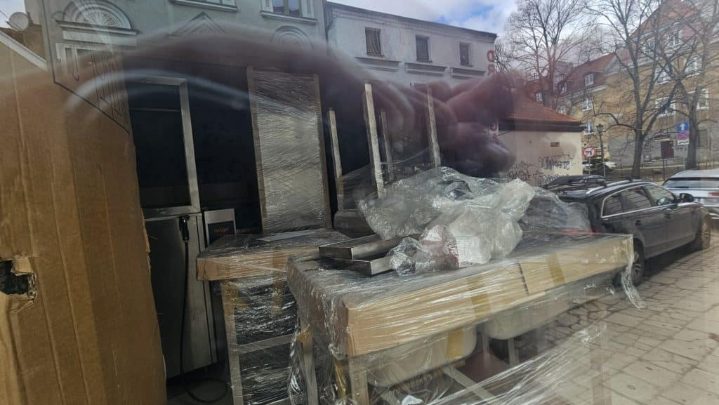 Widok zamkniętego lokalu na Star&oacute;wce, oklejonego folią, z widocznymi sprzętami kuchennymi w środku.