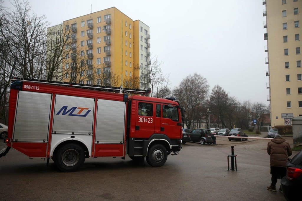 Straż pożarna na miejscu zdarzenia w bloku w Olsztynie, w tle wysokie budynki mieszkalne.