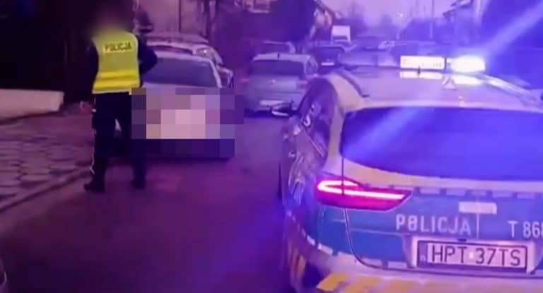 Policja zatrzymuje kierowcę audi po pościgu ulicami Ostr&oacute;dy, w tle inne pojazdy i policjant.