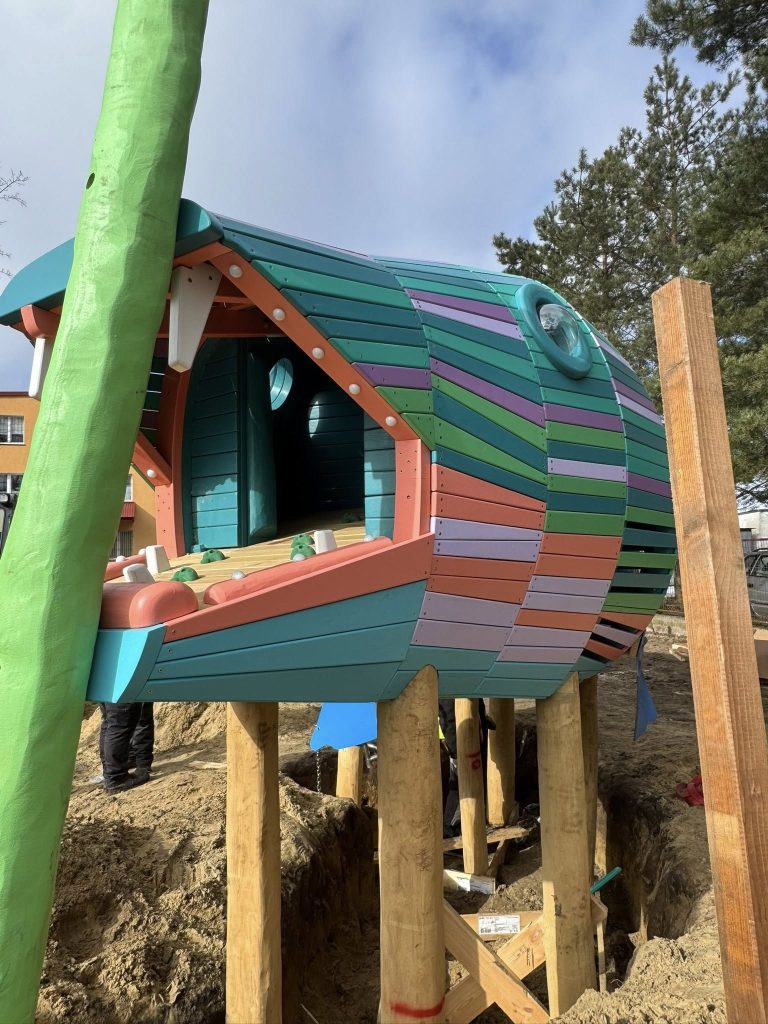 Kolorowa konstrukcja przypominająca rybę na placu budowy w Giżycku.