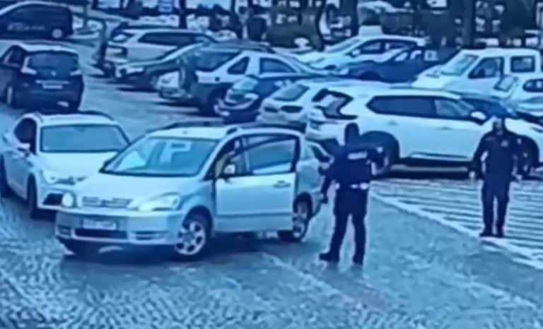 Zdjęcie z monitoringu pokazujące dw&oacute;ch mężczyzn przy samochodach na parkingu, jeden z nich gestykuluje, drugi stoi obok.