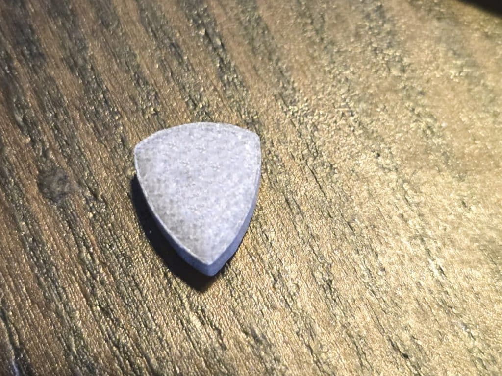 Kamień lub inny przedmiot na drewnianym stole, o nieregularnym kształcie i szarym kolorze.