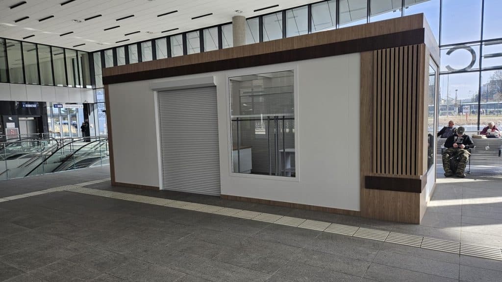 Nowa wyspa handlowa w holu dworca Olsztyn Gł&oacute;wny, z zamkniętymi drzwiami i dużym oknem.