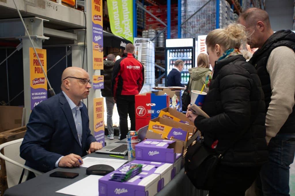 Tłum uczestnik&oacute;w na stoisku podczas targ&oacute;w biznesowych w Gdańsku, rozmowy i prezentacje produkt&oacute;w.