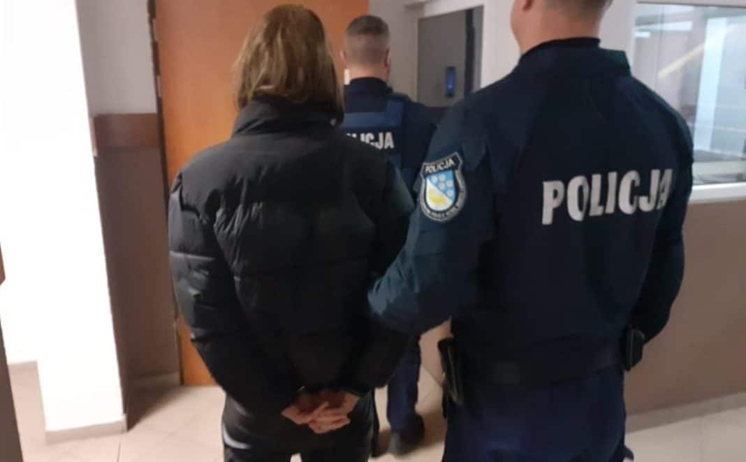 Policjanci zatrzymują młodego mężczyznę w budynku, w tle inni funkcjonariusze.