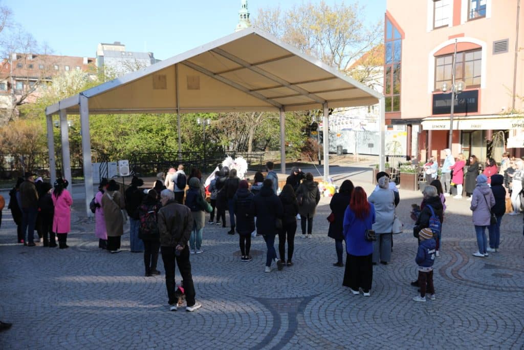 Uczestnicy zgromadzeni na Targu Rybnym podczas wydarzenia upamiętniającego Łukasza Litewkę, przynoszą karmę dla zwierząt.