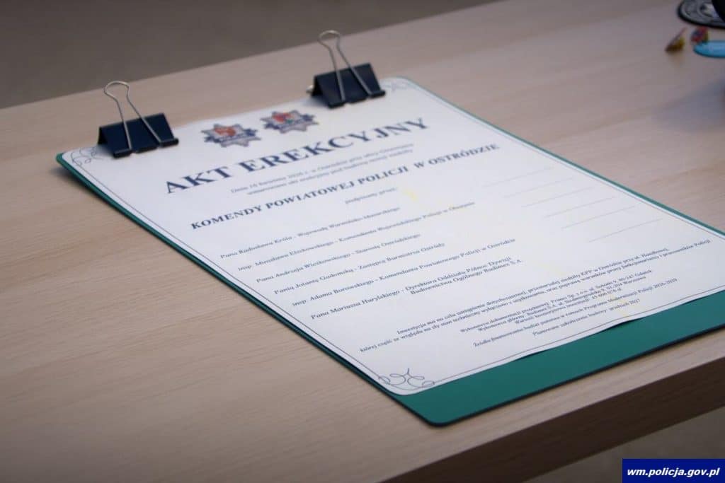 Akt erekcyjny nowej komendy policji w Ostr&oacute;dzie, na stole z dokumentem i klipsami.