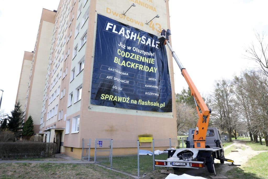 Na budynku zawieszona jest duża banerowa reklama platformy Flashsale.pl, promująca nową usługę w Olsztynie.