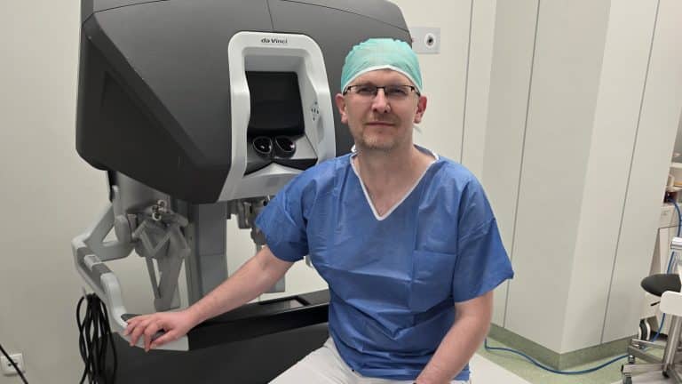 Lekarz w szpitalu obok robota chirurgicznego da Vinci, przygotowującego się do operacji.
