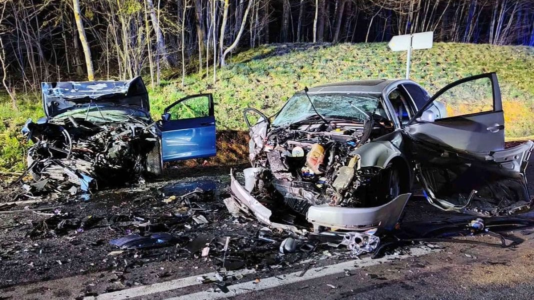 Rozbitych dwa samochody po czołowym zderzeniu na drodze krajowej, widoczne uszkodzenia i rozbicie karoserii.