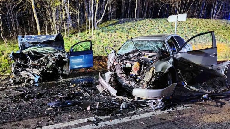 Rozbitych dwa samochody po czołowym zderzeniu na drodze krajowej, widoczne uszkodzenia i rozbicie karoserii.