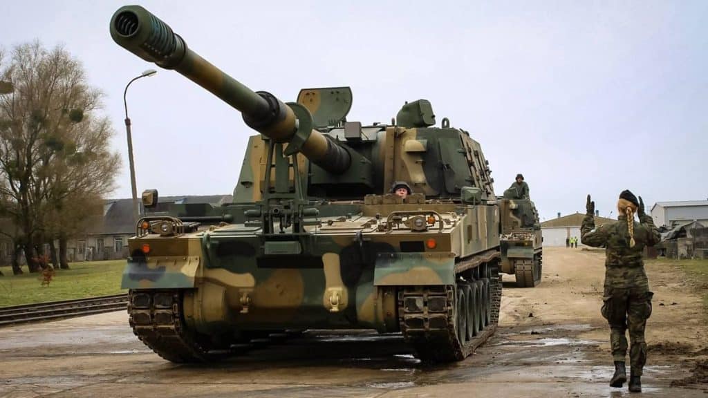 Armatohaubica K9 Thunder na placu wojskowym na Warmii, w tle żołnierz i jednostka wojskowa.