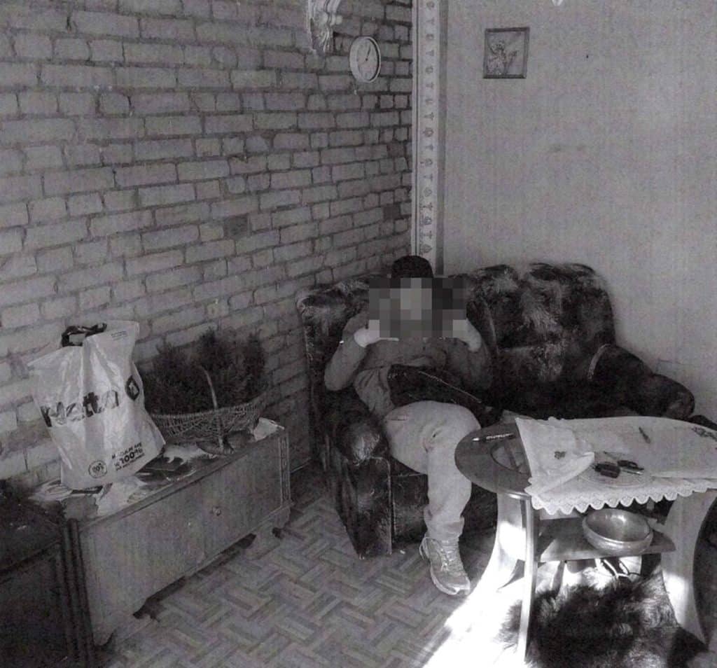 Wnętrze mieszkania z widocznym dziecięcym wzrostomierzem na ścianie, rozgardiaszem i nieuporządkowanym wyposażeniem.