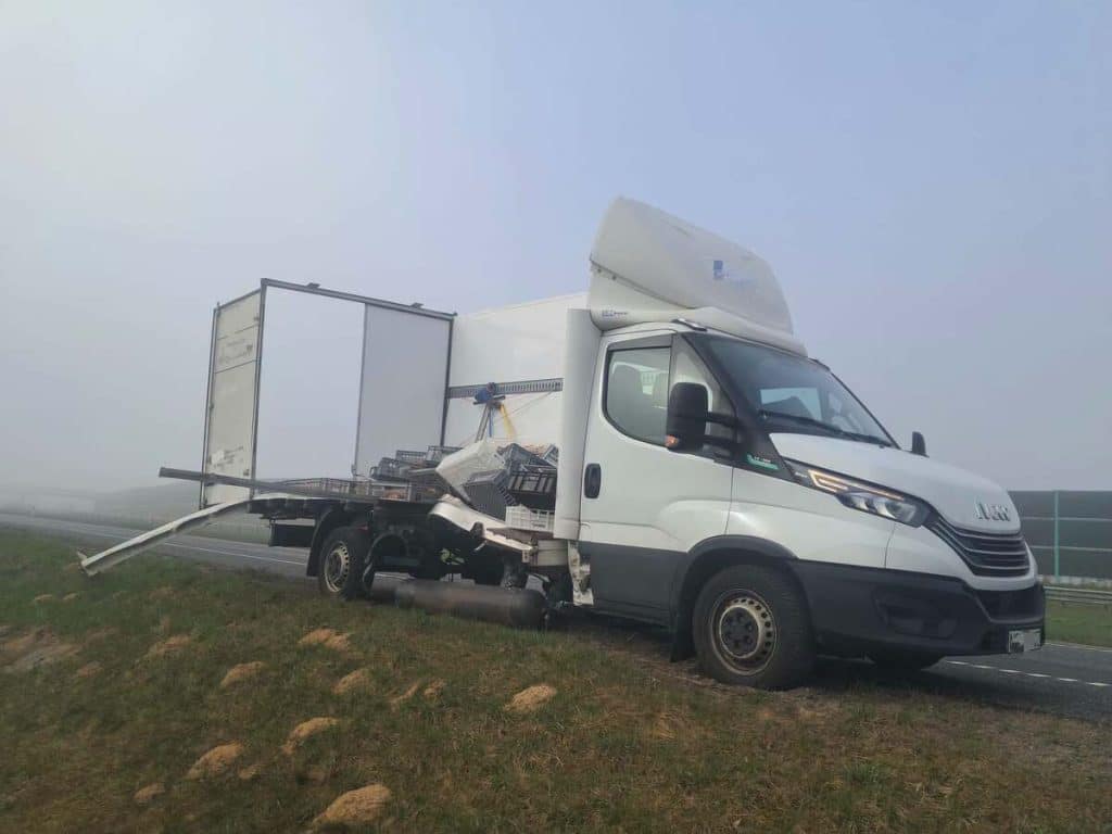 Rozbity samoch&oacute;d dostawczy na poboczu drogi S7 po wybuchu, z rozsypanym ładunkiem na jezdni.