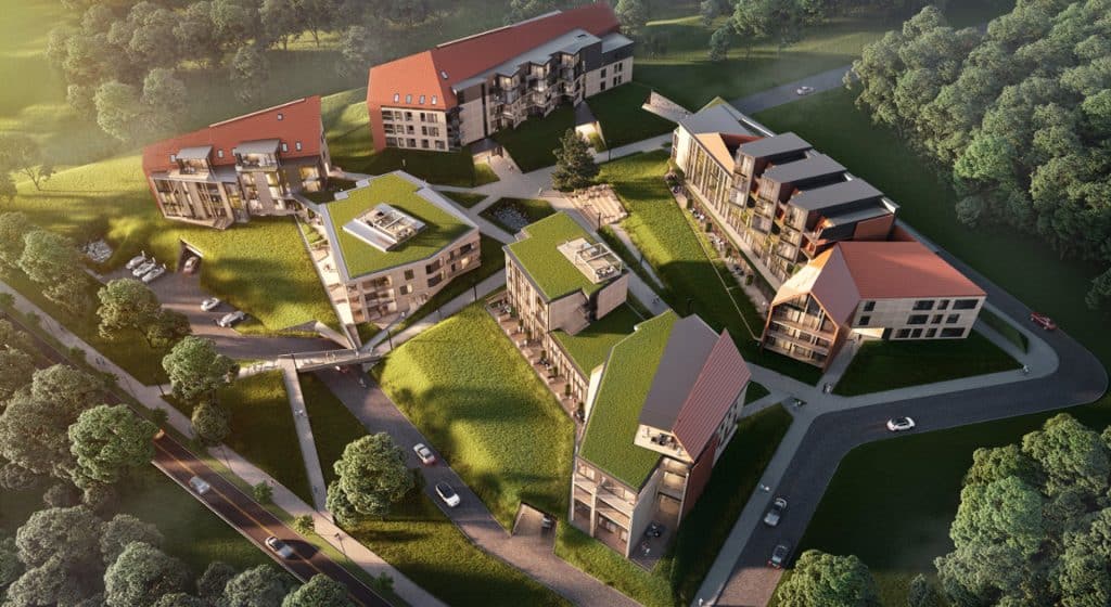 Widok z powietrza na nowoczesne apartamenty nad jeziorem w Mikołajkach, otoczone zielenią i lasami.