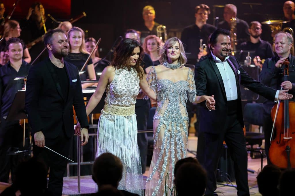 Orkiestra i artyści na scenie podczas koncertu charytatywnego w Olsztynie.