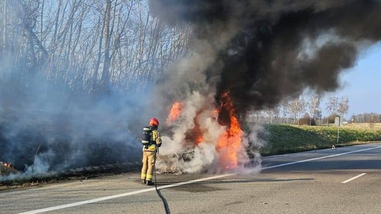 Strażak gaszący samoch&oacute;d osobowy płonący na drodze krajowej nr 16 w Starych Jabłonkach.