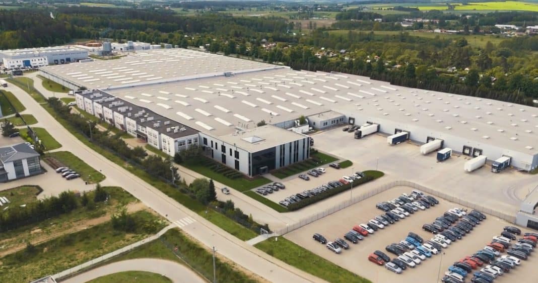 Aerial view of a large industrial complex with parking lots and surrounding greenery.