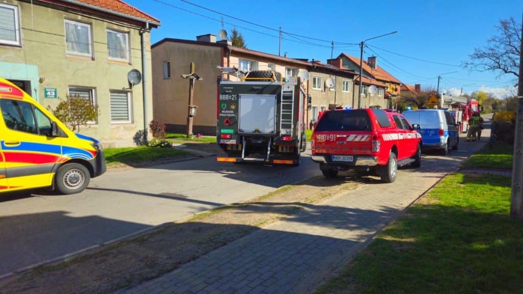 Straż pożarna i pogotowie na ulicy, pojazdy ratunkowe przed blokiem mieszkalnym.