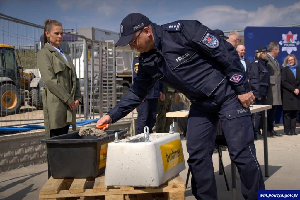 Policjant w uniformie podczas ceremonii budowy nowej komendy w Ostr&oacute;dzie.