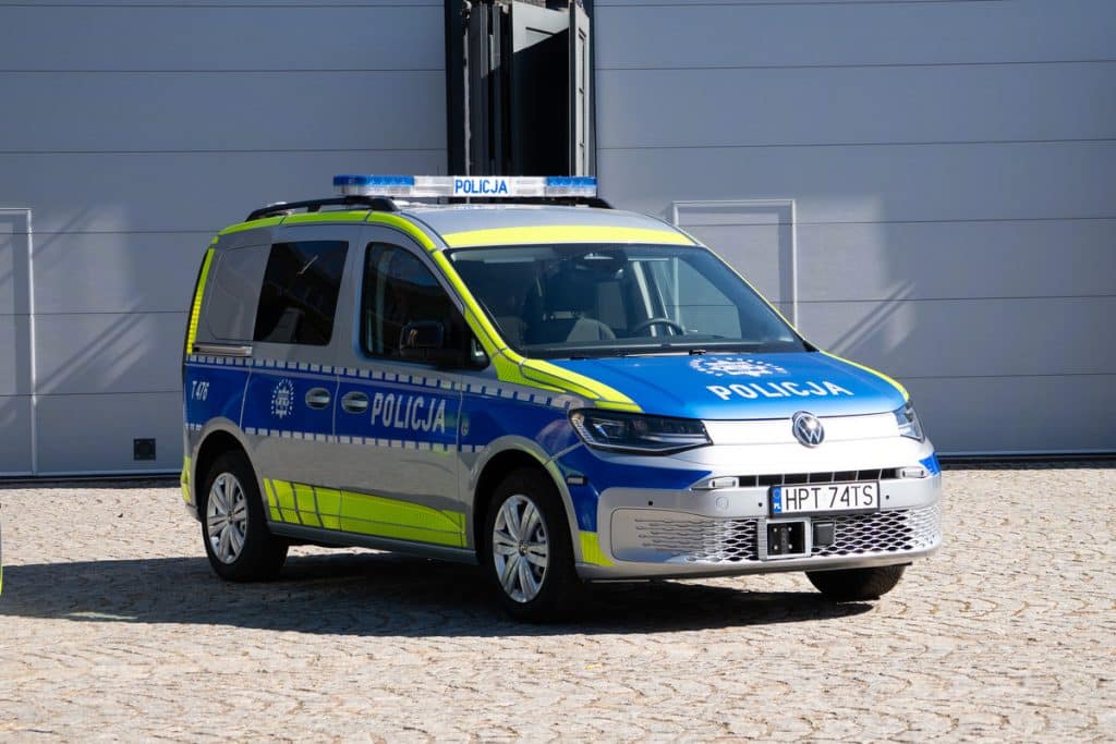 Nowoczesny radiow&oacute;z policyjny na Mazurach, w biało-niebieskich barwach, z oznakowaniem i światłami na dachu.