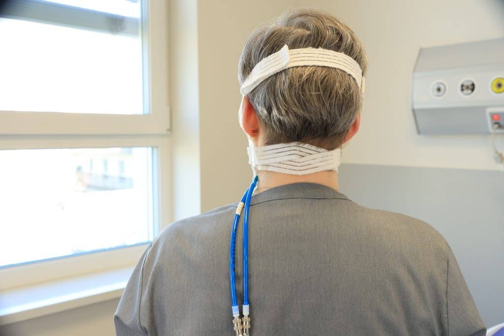 Pacjentka z opaskami na głowie podczas leczenia w szpitalu, widok od tyłu.