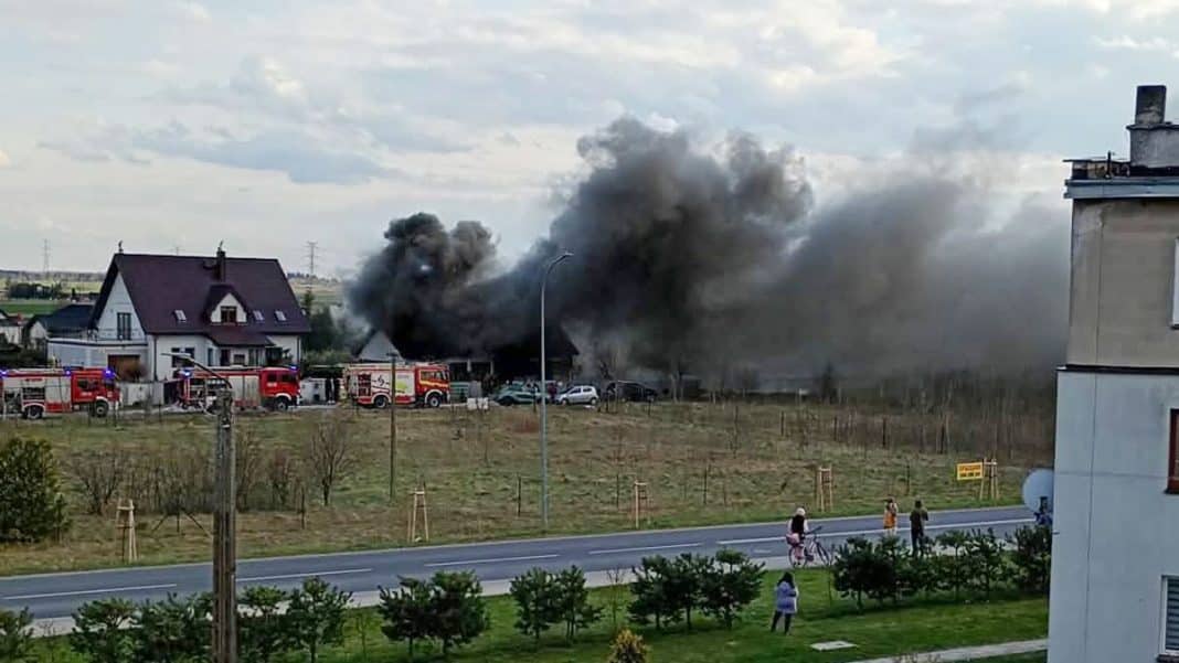 Gęste kłęby dymu unoszą się nad domem podczas pożaru na Mazurach, widoczne z daleka.