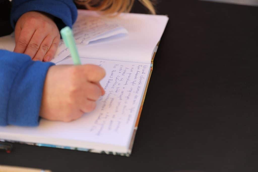 Osoba wpisująca się do księgi pamiątkowej podczas wydarzenia na Targu Rybny w Olsztynie.