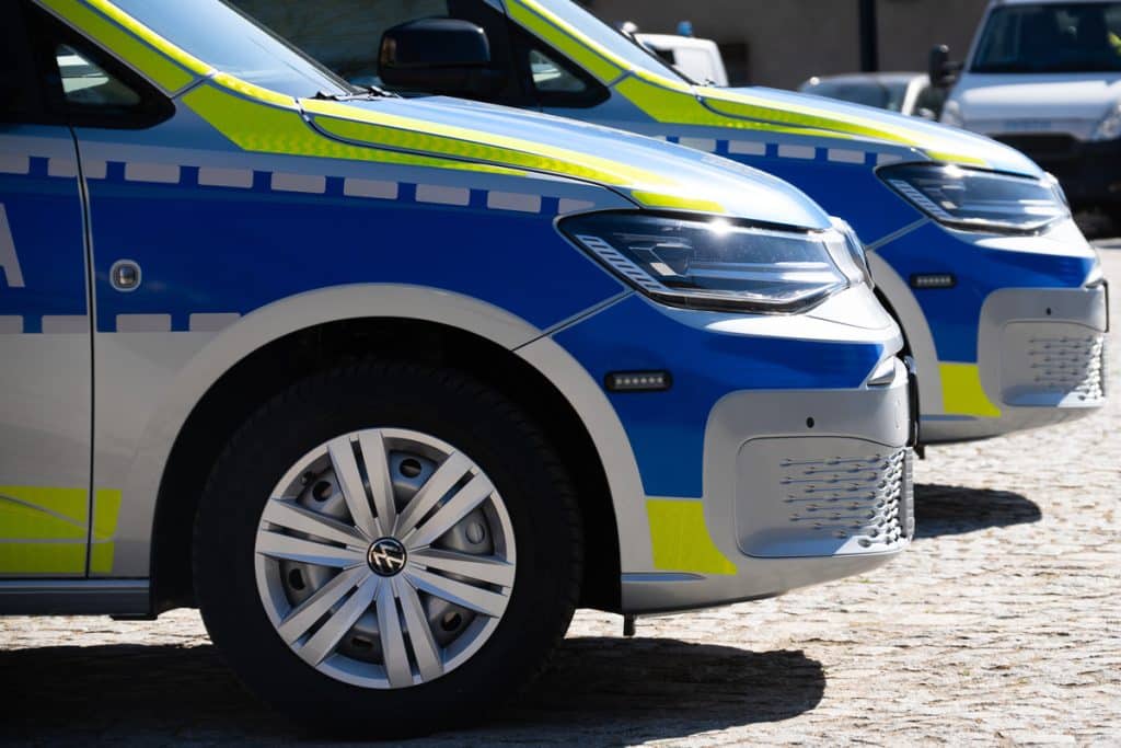 Dwa nowe policyjne radiowozy na Mazurach, w niebiesko-ż&oacute;łtych barwach, zaparkowane na placu, widoczne z bliska.