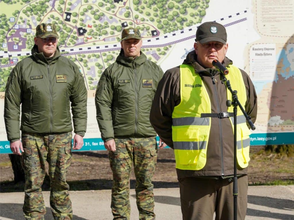 Grupa strażnik&oacute;w granicznych i leśnik&oacute;w podczas wydarzenia sadzenia drzew w Wilczym Szańcu.