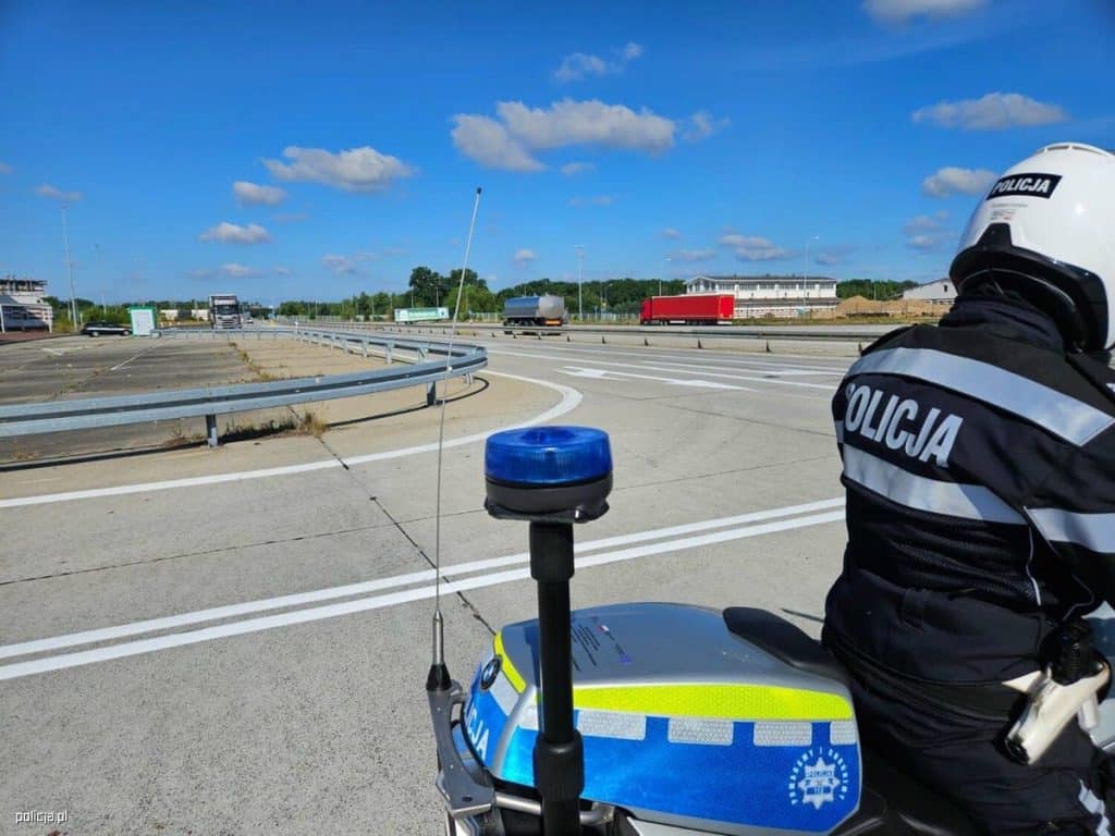 Policjant na motocyklu patroluje drogę podczas kontroli w słoneczny dzień.