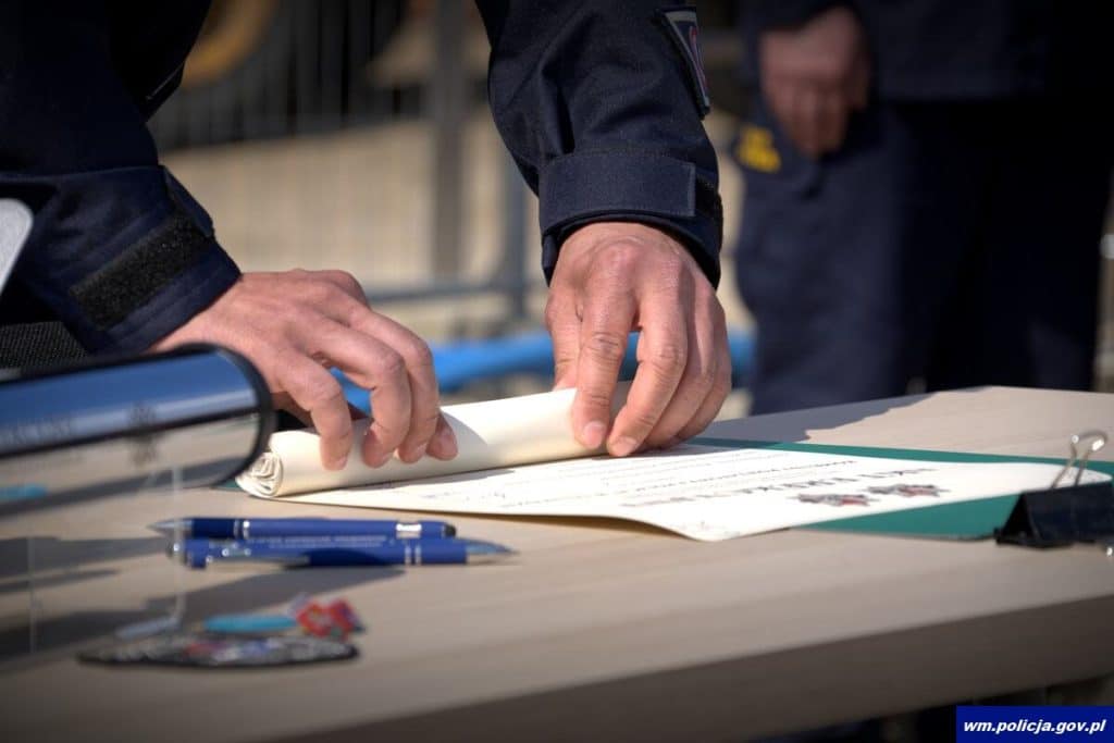 Osoby w mundurach policji podpisują dokument na uroczystości rozpoczęcia budowy nowej komendy w Ostr&oacute;dzie.