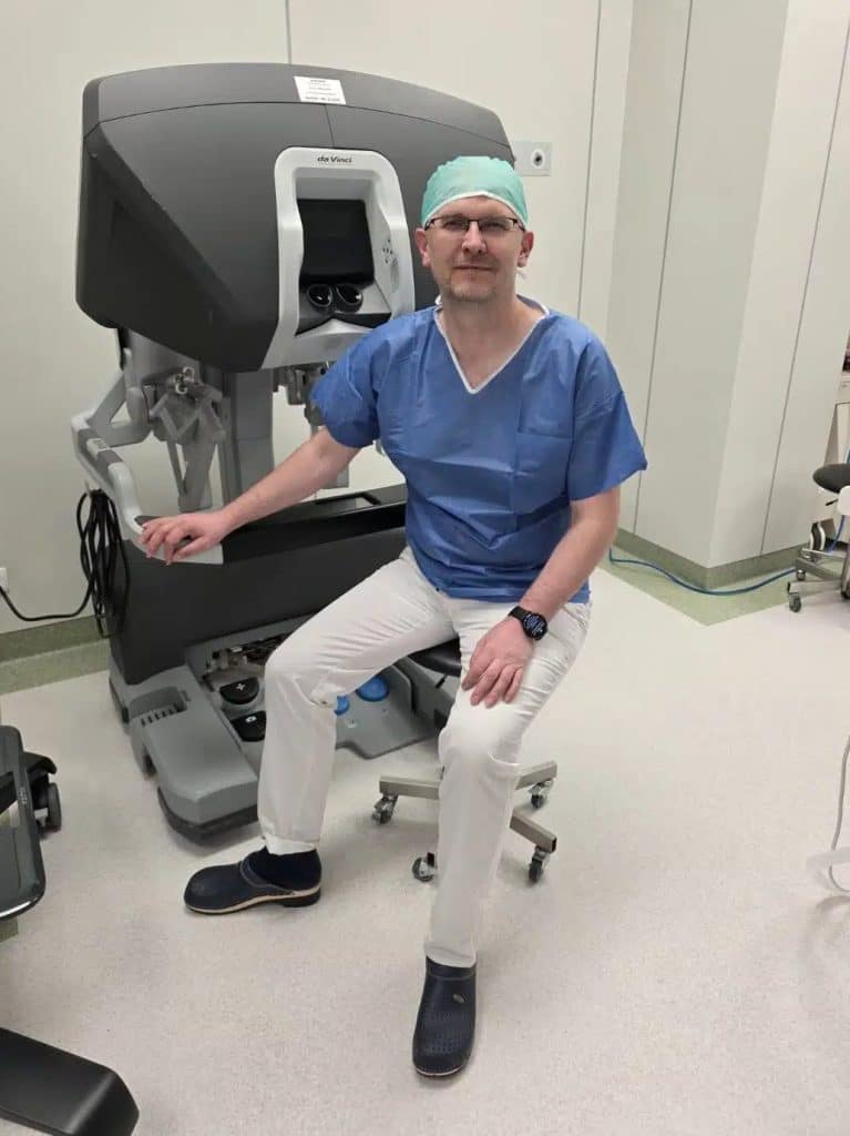 Lekarz siedzi obok robota chirurgicznego da Vinci w szpitalu, przygotowując się do operacji.
