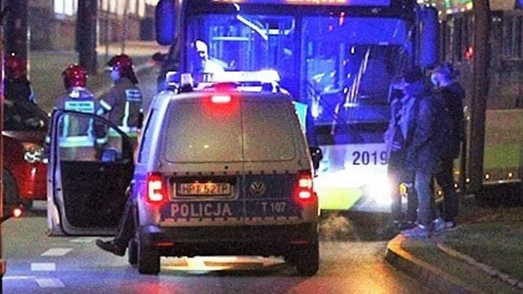 Policja i służby na miejscu zdarzenia z udziałem rowerzysty i autobusu, nocne oświetlenie, wypadek na ulicy.