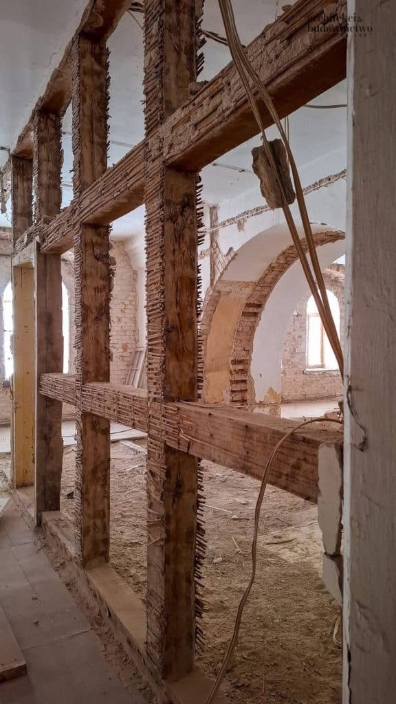 Wnętrze remontowanego koszarowca w Twierdzy Boyen, widoczne prace konstrukcyjne i ceglane ściany.