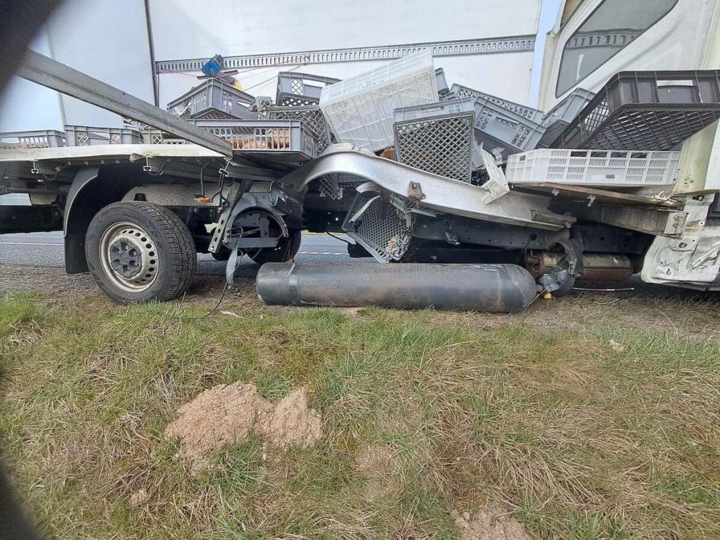 Uszkodzony samoch&oacute;d dostawczy po wybuchu na drodze S7, z rozsypanym ładunkiem na jezdni.