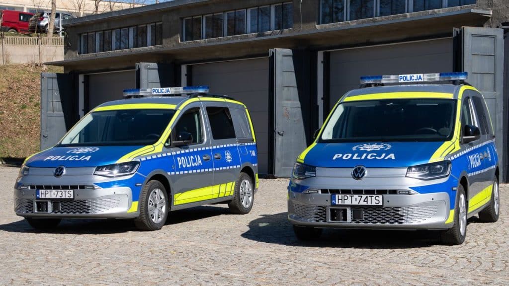 Dwa nowe radiowozy policyjne na Mazurach, w policyjnych barwach, zaparkowane na placu.