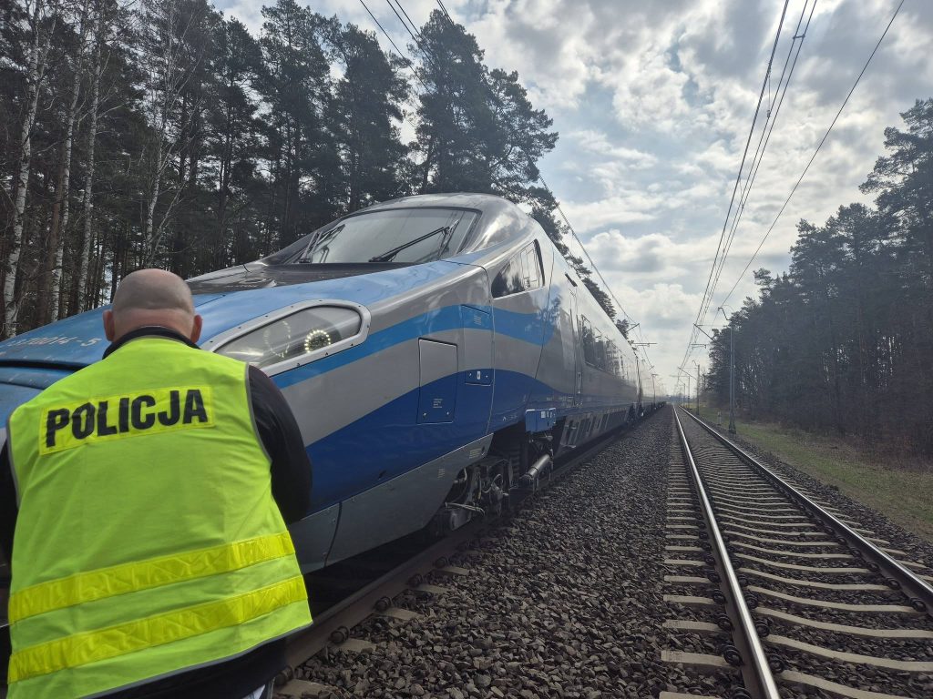 Nastolatek leżący na torach po potrąceniu przez pociąg Pendolino, w tle linie kolejowe i las.