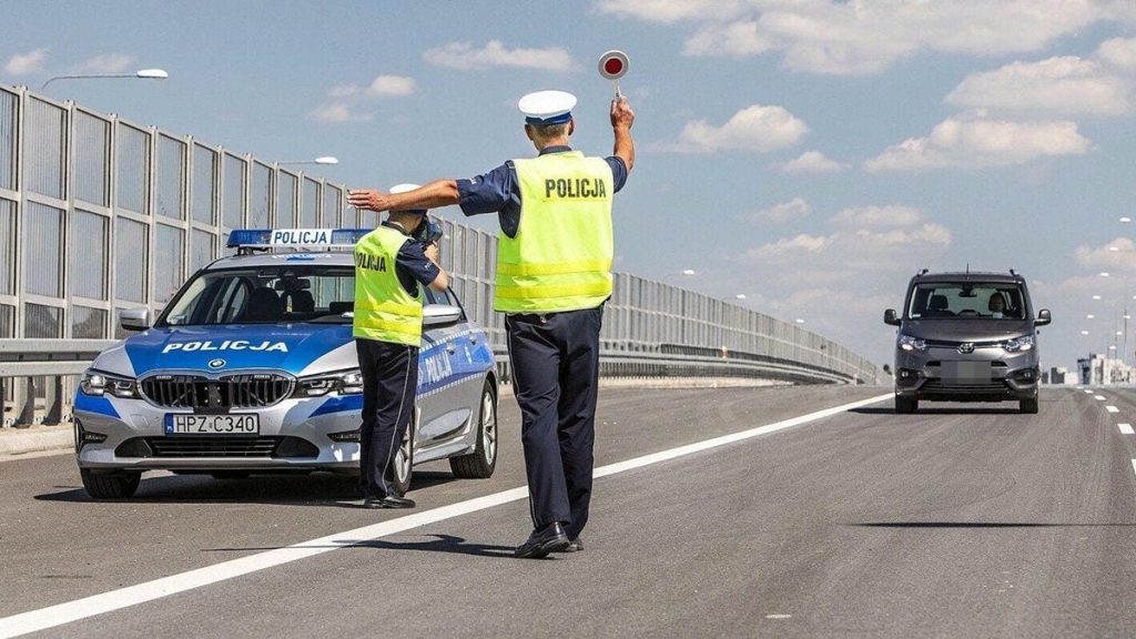 Policjant zatrzymuje kierowcę do kontroli na drodze podczas maj&oacute;wki.