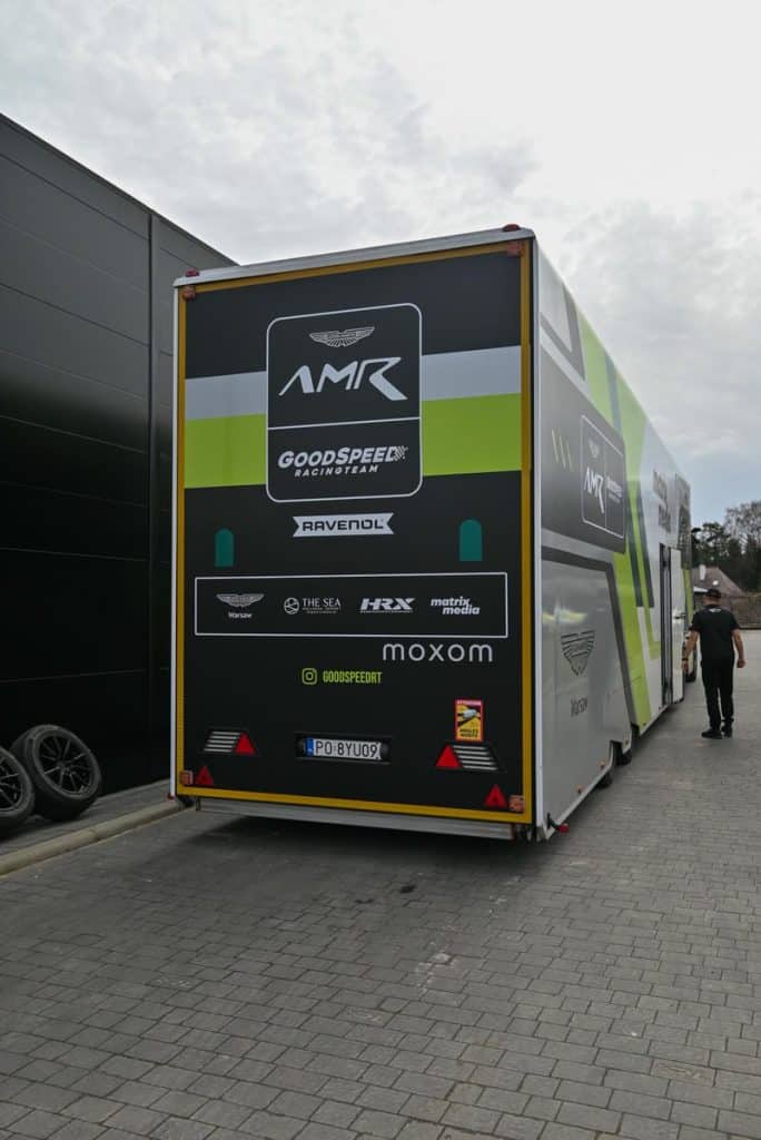 Transporter z logo Aston Martin i GoodSpeed Racing Team pod Olsztynem, przygotowujący wyścigowe modele GT3 i GT4.