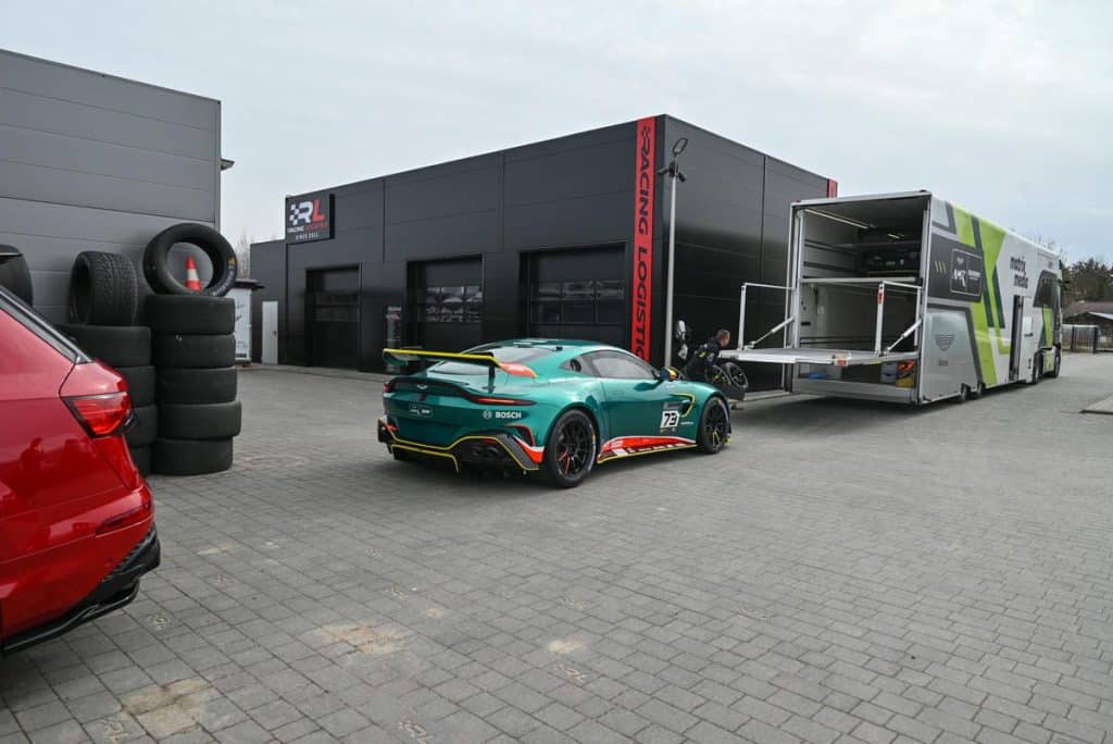 Wyścigowe Aston Martiny GT3 i GT4 na parkingu pod Olsztynem, przygotowywane do start&oacute;w.