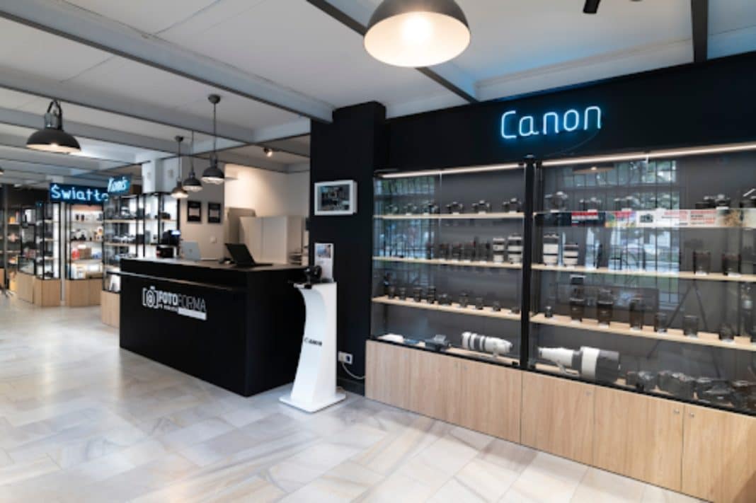 Sklep fotograficzny z wystawą sprzętu marki Canon i stoiskiem z aparatami.