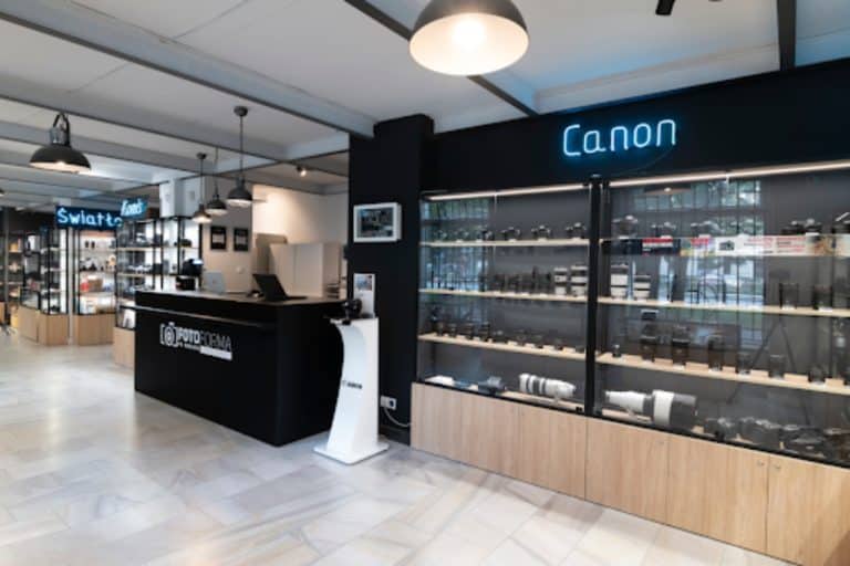 Sklep fotograficzny z wystawą sprzętu marki Canon i stoiskiem z aparatami.