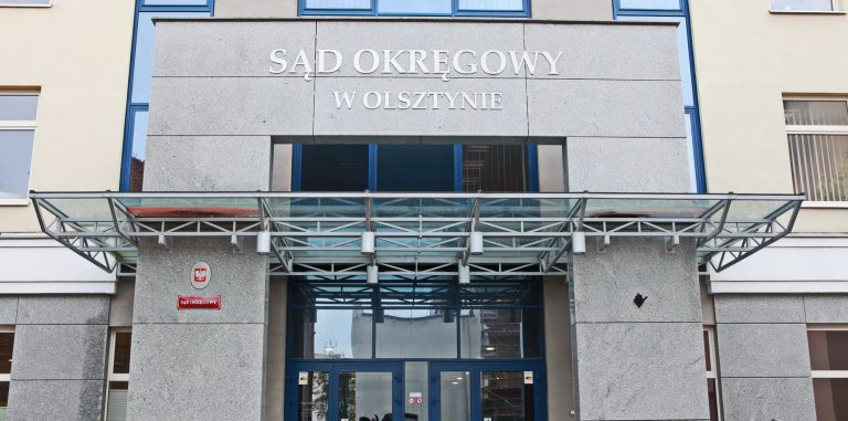 Widok na budynek Sądu Okręgowego w Olsztynie, frontowa elewacja z nazwą instytucji.