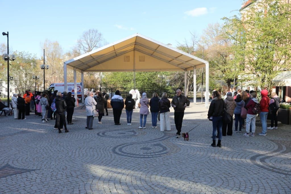 Mieszkańcy zgromadzeni na Targu Rybny w Olsztynie podczas wydarzenia upamiętniającego Łukasza Litewkę, przynoszą karmę dla zwierząt.