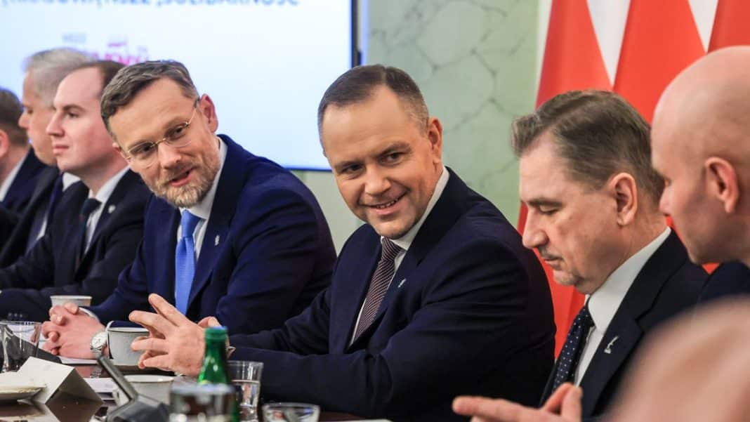 Grupa mężczyzn w formalnych ubraniach podczas spotkania, z uśmiechami i rozmową.