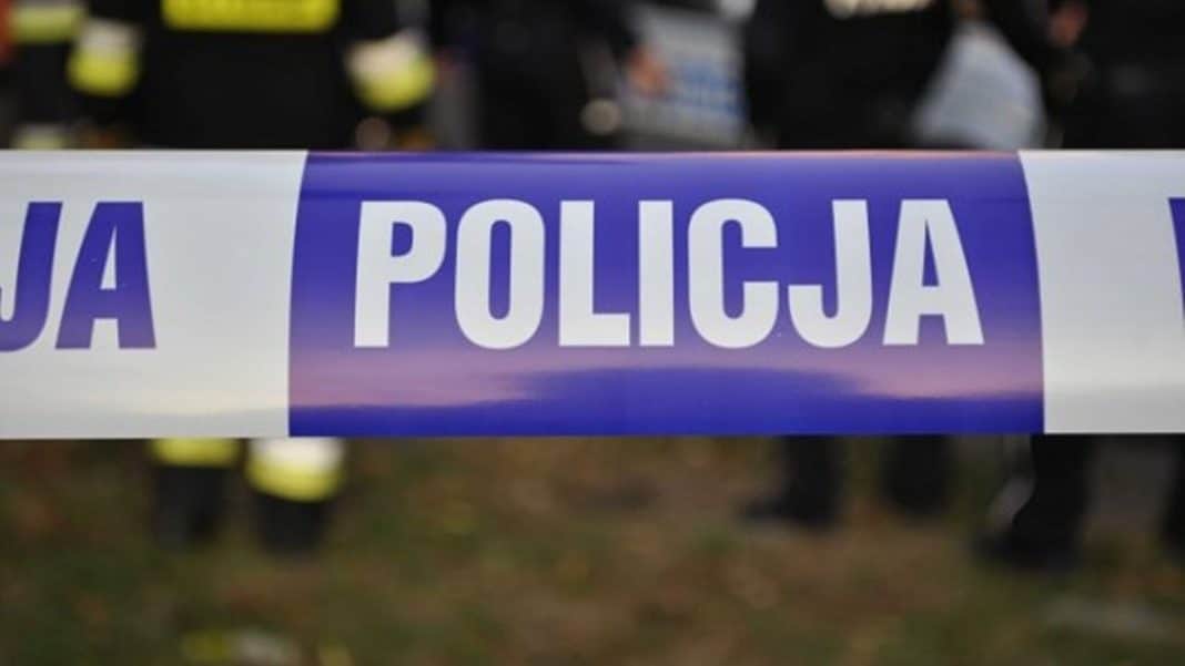 Policja z taśmą na miejscu zdarzenia, w tle służby i mieszkańcy.