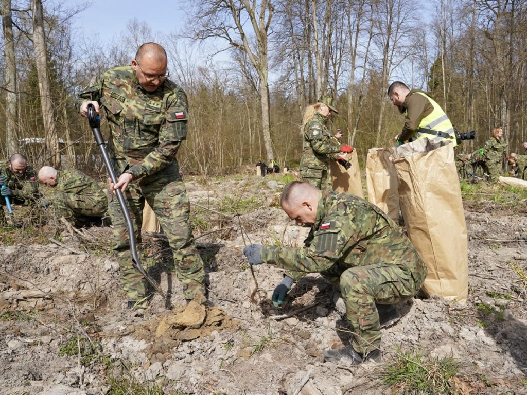 Strażnicy i młodzież sadzą drzewa w lesie na Mazurach podczas akcji z okazji Światowego Dnia Ziemi.