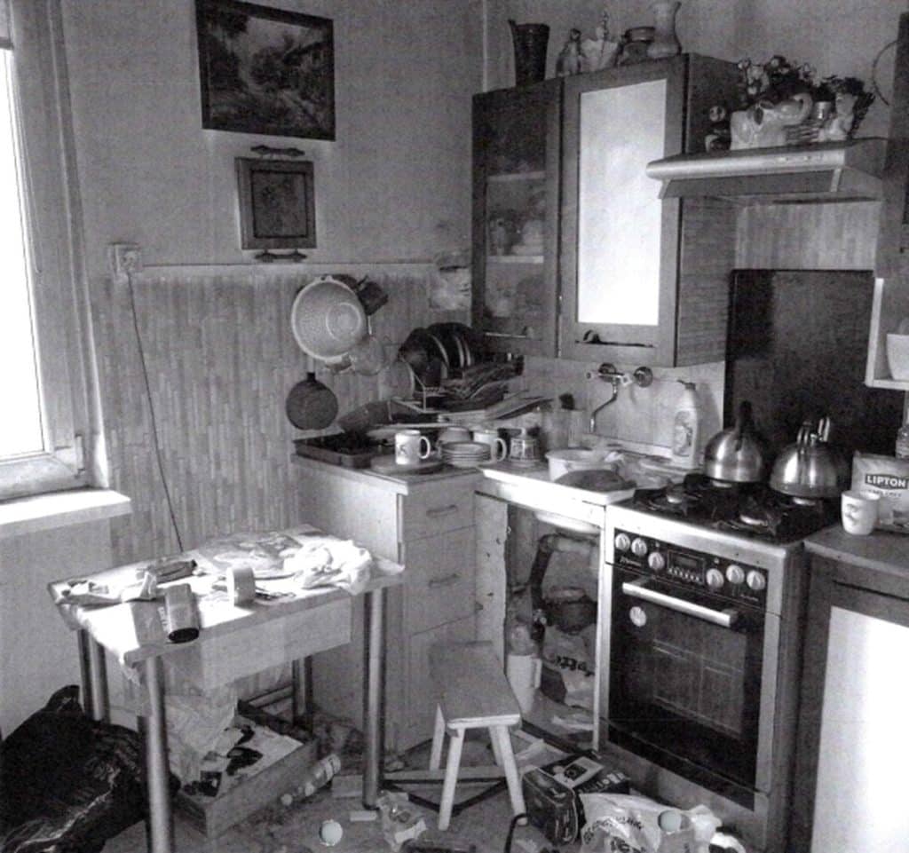 Zagracone i nieuporządkowane wnętrze kuchni z widocznym sprzętem i odpadami.